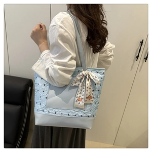 Detail of light blue tote bag with decorative patterned silk scarf on the handle