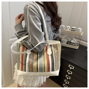 Sac fourre-tout coloré en paille tissée avec poignées en cuir blanc porté par un mannequin