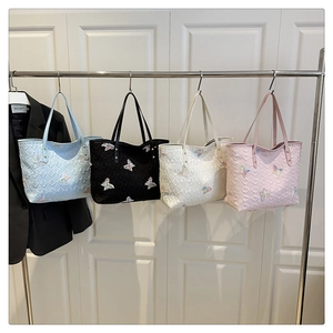 Détail de quatre sacs cabas avec broderie papillon en bleu, noir, blanc et rose poudré