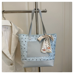 Close-up of light blue pleated tote bag with decorative scarf and exterior pocket