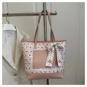 Detail of quilted tote bag featuring a pink leather pocket and decorative scarf handle