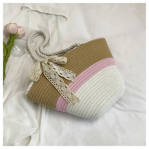 Détail d'un sac cabas tissé tricolore avec nœud en dentelle et tulipe rose