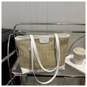 Détail d'un sac cabas en paille tissée avec finitions en cuir blanc et étiquette mode