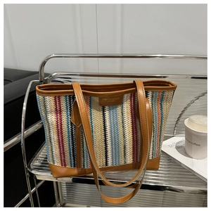 Détail du sac cabas tissé à rayures colorées avec bordure en similicuir marron et étiquette