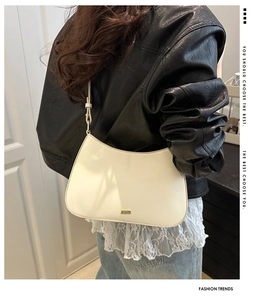 Detail of cream white underarm bag with gold metal logo and minimalist matte finish