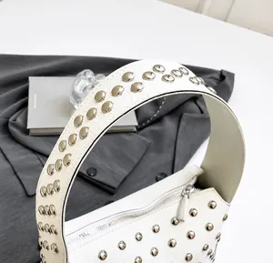 Dettaglio del manico in pelle bianca con rivetti argentati su una borsa tote vintage