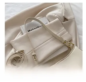 Detail of cream white leather shoulder bag with gold hardware and adjustable strap
