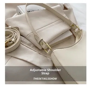 Close-up of adjustable cream leather strap with gold buckle on a minimalist shoulder bag