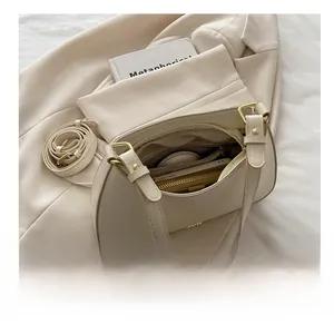 Detail view of cream leather crescent bag interior with compartments and gold hardware