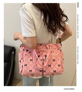 Detail of pink corduroy tote bag with bow prints worn by a model in a cozy setting