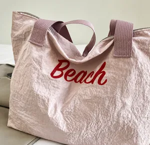 Dettaglio della borsa tote in nylon rosa con scritta Beach rossa e trama del tessuto
