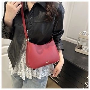 Detail view of burgundy vintage hobo bag with gold logo on black leather jacket