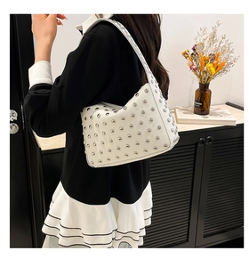 Vista posteriore di una modella che indossa una borsa bianca con borchie in un interno