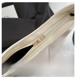 Close-up of golden zipper closure on minimalist ivory leather tote bag with dark lining