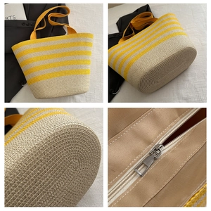Detail shot of yellow striped straw tote bag showing zipper closure and woven texture