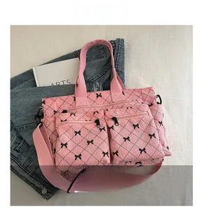 Detail of pink corduroy tote bag with black bow patterns and functional front zipper pockets