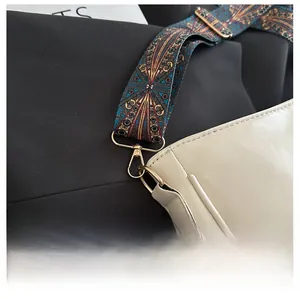 Macro detail of bohemian embroidered shoulder strap with gold hardware on beige bag