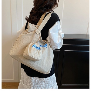 Detail of beige large tote bag with blue Beach text and matching drawstring pouch