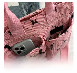 Detailed shot of pink corduroy tote bag featuring bow patterns and functional front pockets