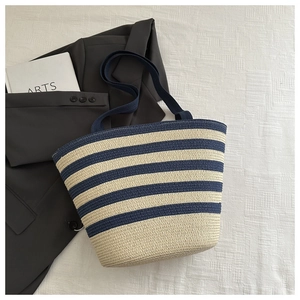 Top view of large straw tote bag with navy blue and cream stripes on white fabric