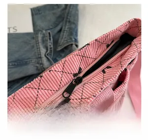 Detail of metal zipper closure on pink corduroy tote bag with black bow pattern