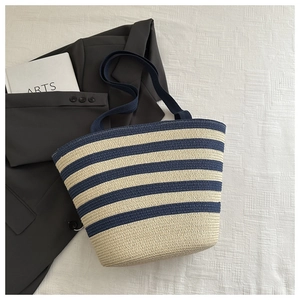 Detailed close-up of woven tote bag with navy blue and beige stripes on white fabric