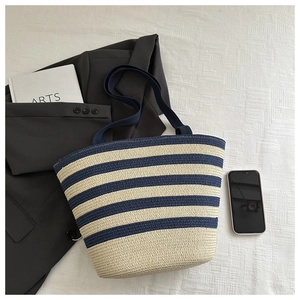 Flat lay of striped woven tote bag with navy blue straps and daily fashion accessories