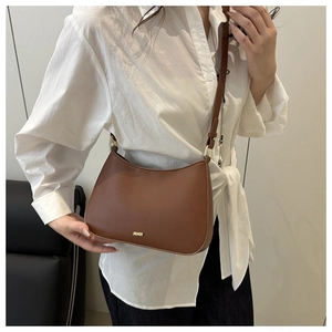 Detail of JIADAOR brown shoulder bag featuring matte leather and golden logo on a model