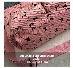 Close-up of pink corduroy shoulder bag with adjustable strap and black bow patterns