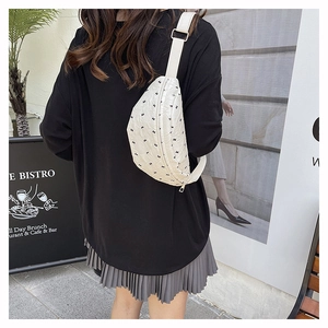 Outdoor shot of a white quilted crossbody bag with black bow patterns on a model's back
