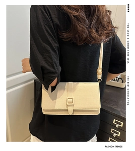 Détail du sac crème avec texture tissée et boucle carrée décorative sur le rabat