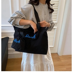 Dettaglio della borsa tote nera e mini pochette coordinata con ricamo Beach blu