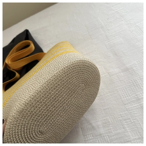 Detailed close-up of handmade straw shoulder bag with yellow stripes and wide strap