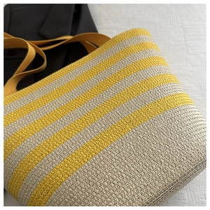 Close-up of a woven tote bag with yellow and beige stripes and durable fabric straps