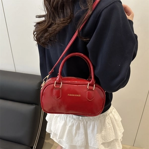 Red cylindrical mini Boston bag with shiny finish and adjustable shoulder strap