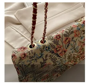 Nahaufnahme der goldenen Kette und Blumenstickerei auf der ethnischen kleinen Tasche