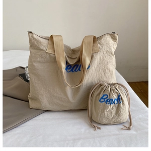 Detail view of the beige canvas tote bag set with Beach text and drawstring pouch