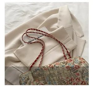Detailaufnahme des gewebten Kettenriemens und der Blumenstickerei an der Handtasche