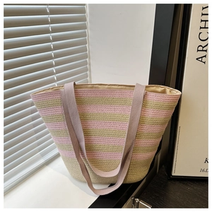 Detail of pink and green striped woven tote bag with purple straps in sunlight