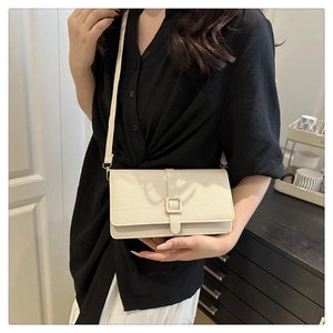 Sac bandoulière rectangulaire beige avec boucle de ceinture porté par un mannequin