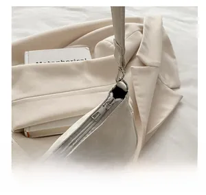 Detail of silver zipper and snakeskin textured finish on off-white crossbody bag