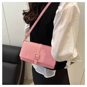 Vue détaillée d'un sac bandoulière rose texturé porté par un mannequin dans un cadre minimaliste