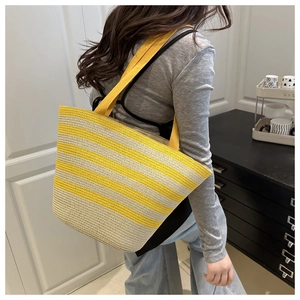 Close-up of yellow and beige striped straw tote bag showing texture and wide strap