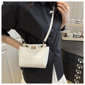 Détails du cuir blanc grainé et fermoir doré rotatif sur le petit sac à bandoulière chic
