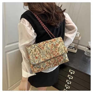 Detailansicht der Vintage-Blumenstickerei und eleganten Metallkette an einer Schultertasche