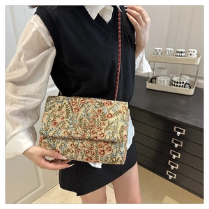 Detail of floral tapestry underarm bag with red metal chain strap and vintage pattern