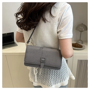 Sac à bandoulière gris texturé porté par un mannequin dans un cadre moderne épuré