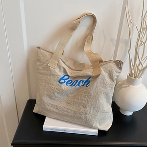 Large beige canvas tote bag with blue Beach lettering and unique pleated texture