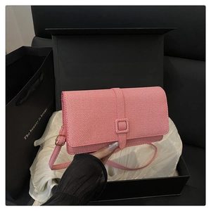 Détail du sac à rabat rose en texture sergée avec sangle assortie sur boîte noire