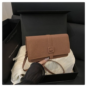 Détail d'un petit sac bandoulière marron texturé dans un coffret cadeau de luxe